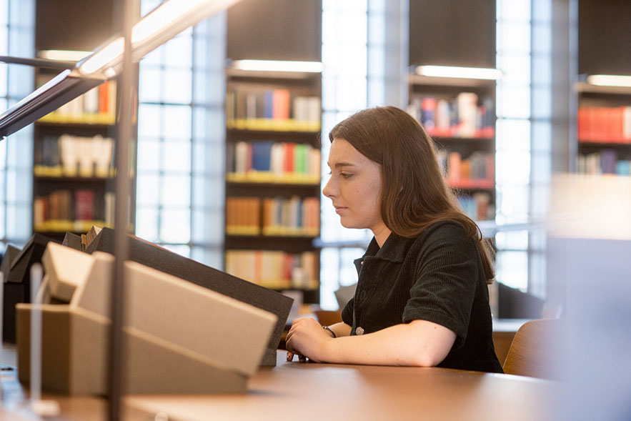 A woman examines a book in a reading room
